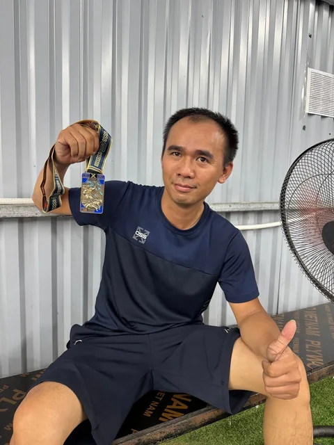 A finisher holding their X Challenge medal